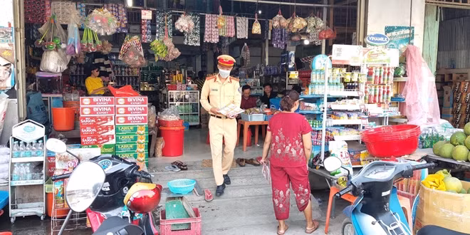 Cán bộ Cảnh sát giao thông phát tờ rơi, tuyên truyền đến các hộ dân.
