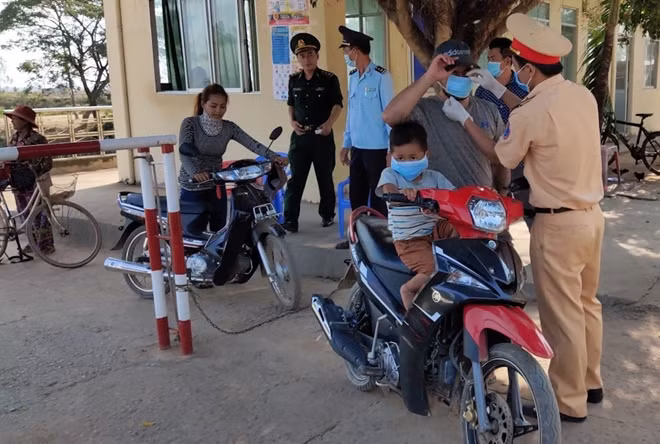 Cán bộ Cảnh sát giao thông phát khẩu trang y tế cho người dân qua lại tại cửa khẩu Thông Bình, Tân Hồng, Đồng Tháp.