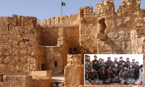 Lá cờ đen IS phía trên một thành lũy ở Palmyra, cùng với bức ảnh binh sĩ Syria quỳ gối (ở góc phải).