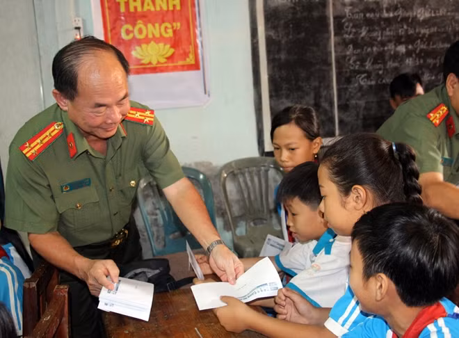 Đại tá Trần Kim Thẩm trao quà cho các em học sinh.