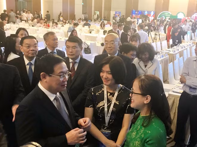 Phó Tổng giám đốc Vietcombank Phùng Nguyễn Hải Yến (thứ 2 từ phải sang) giới thiệu và hướng dẫn Phó Thủ tướng Vương Đình Huệ cùng các đại biểu tham quan gian hàng giới thiệu của Vietcombank tại Hội thảo