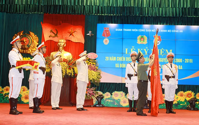 Thừa ủy quyền của Chủ tịch nước,Thứ trưởng Nguyễn Văn Sơn gắn Huân chương Lao dộng hạng Ba lên lá cờ truyền thống'.