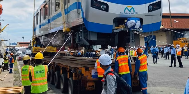 Các công nhân, kỹ sư đang hạ đầu tàu xuống xe siêu trường siêu trọng