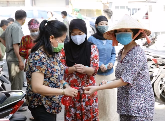 Trước khi vào nhận gạo, người dân được hướng dẫn rửa tay và giữ khoảng cách.