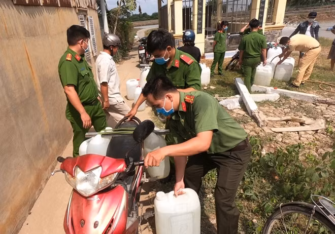 Cán bộ chiến sĩ Công an xã phụ giúp người dân đưa nước lên xe.