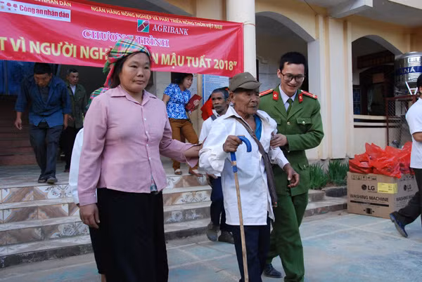 Đoàn viên thanh niên Công an huyện Tuần Giáo dìu bà con xã Mường Mùn đến nhận quà Tết từ đoàn công tác.