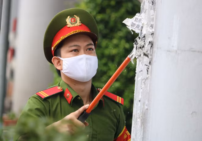 Cán bộ Công an xóa quảng cáo “tín dụng đen” tại chân cầu Nguyễn Tri Phương (quận 5, TP Hồ Chí Minh).