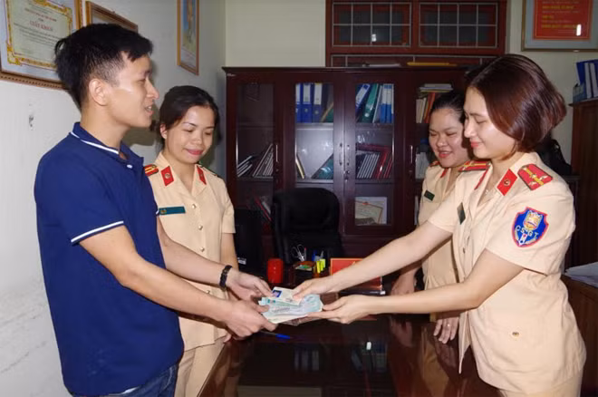 Cán bộ Phòng CSGT Công an Hà Nam trao trả tài sản cho anh Trần Văn Quỳnh.