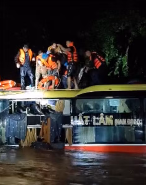 Lực lượng cứu hộ Công an huyện Bố Trạch đưa số hành khách trên xe bị kẹt do nước lũ đến nơi an toàn.