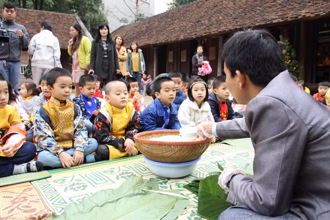 Trẻ em thích thú xem gói bánh chưng cùng nghệ nhân ngày Tết.