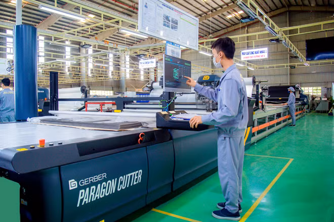 Công nhân điều khiển máy cắt vải CNC tại nhà máy ghế ô tô.