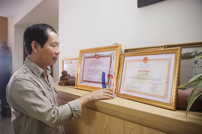 Nhà điêu khắc Vũ Đại Bình bên 2 bằng khen, giải thưởng của Ban Tuyên giáo Trung ương và Bộ Công an cho công trình.