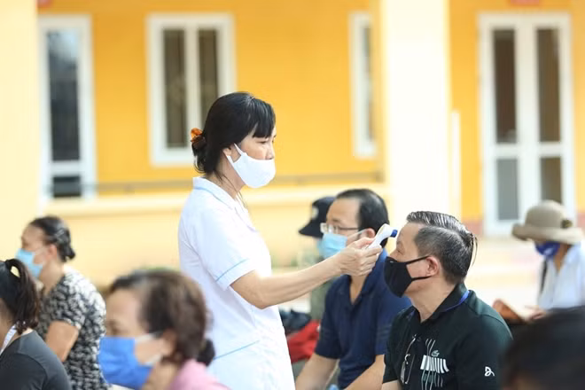 Trước khi làm thủ tục xét nghiệm nhanh COVID-19 người dân được kiểm tra thân nhiệt