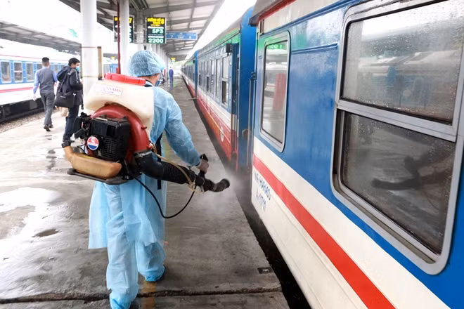 Nhân viên y tế phun thuốc diệt khuẩn bên ngoài các đoàn tàu