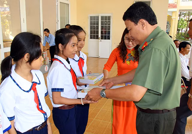 Đại diện Báo CAND động viên, trao tặng tập, viết cho các em học sinh.