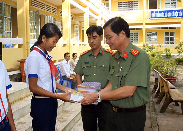 Thượng tá Phan Văn Thanh, Phó trưởng Công an huyện Mỹ Tú trao tặng tập cho các em học sinh.