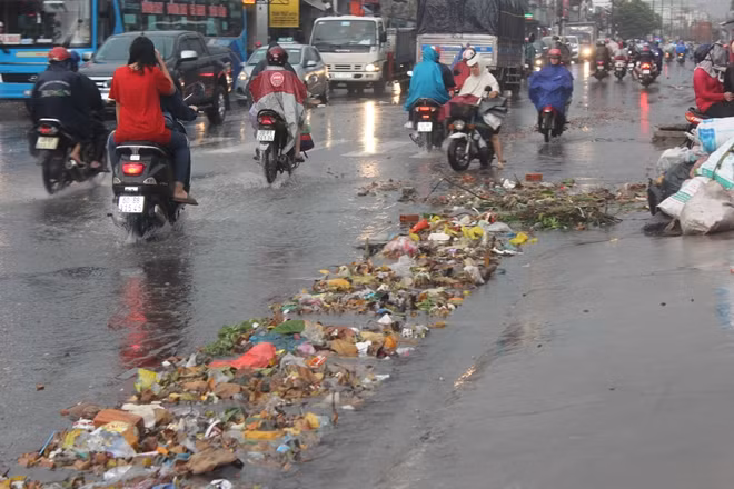 Rác thải trôi ra đường bịt kín cửa thoát nước gây ngập.