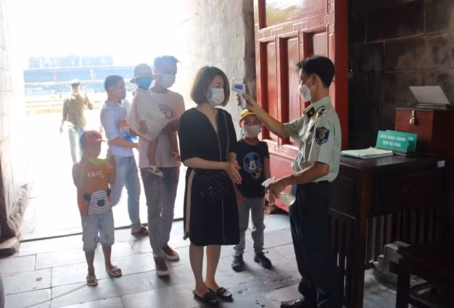 Trước khi vào tham quan di tích, các du khách được bảo vệ đo thân nhiệt.