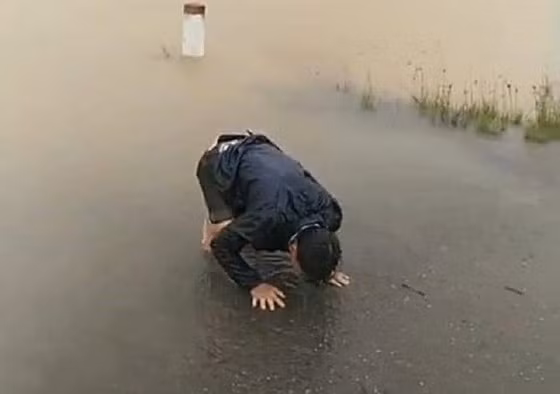 Hình ảnh anh Minh quỳ khóc sau khi ghe chở vợ đi sinh con không may bị lật giữa dòng nước lũ chảy xiết.