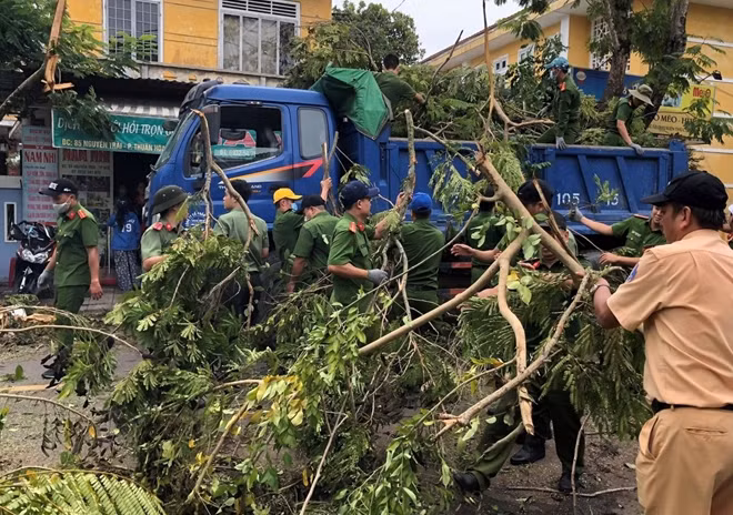 Lực lượng Công an thu dọn cây cối gãy đổ trên các tuyến phố đưa lên xe tải.