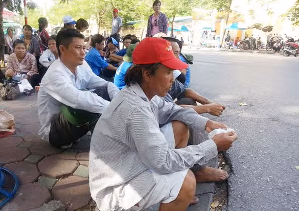 Người nhà thí sinh ngồi chờ con giữa trời nắng nóng.
