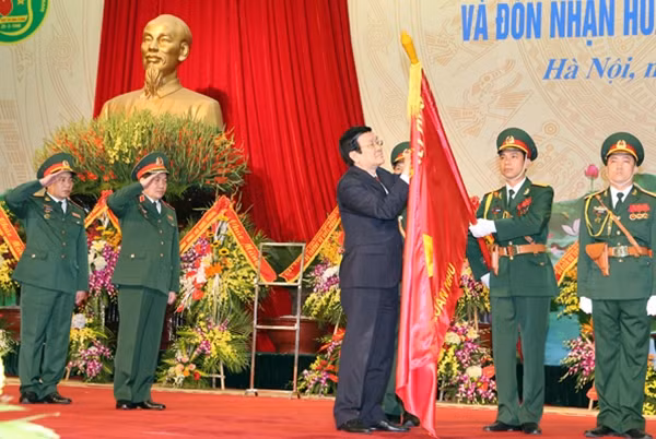 Chủ tịch nước Trương Tấn Sang gắn Huân chương Quân công hạng Nhì lên Quân kỳ quyết thắng của ngành Quân nhu Quân đội. Ảnh: TTXVN
