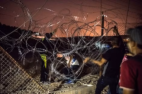 Người Palestine chui qua hàng rào thép gai để vào Israel.