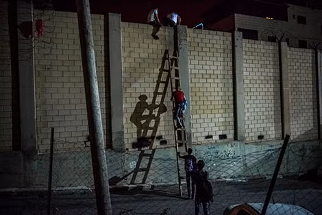 Người lao động Palestine bất hợp pháp leo cầu thang vượt bức tường an ninh ngăn cách Israel và Bờ Tây.