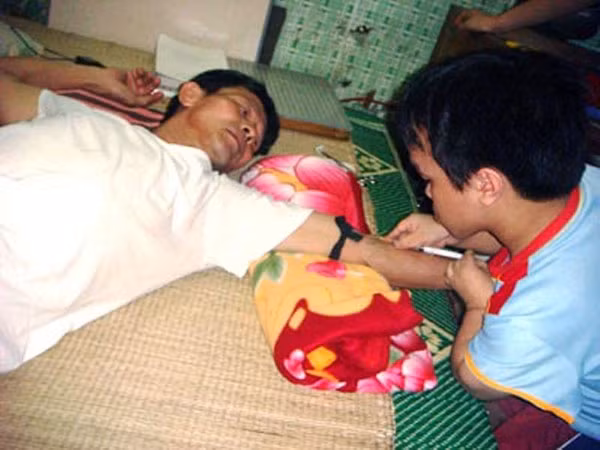 Ngô Văn Định đang thực tập tiêm cho bố (thời điểm tháng 5-2010).