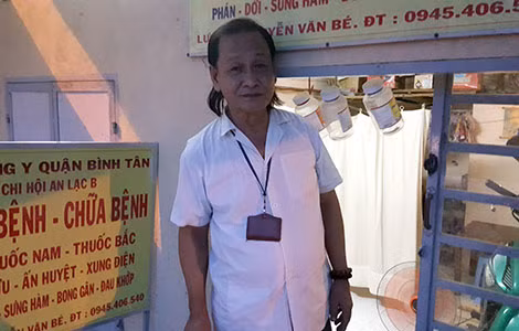 Lương y Nguyễn Văn Bé trước cửa ra vào và những chai nhựa treo lủng lẳng để tránh bị thương.