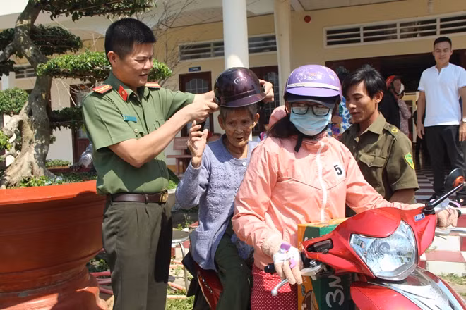 Thiếu tá Nguyễn Văn Bình, cùng Công an xã, giúp đỡ một cụ bà ra xe máy để người thân đưa về.