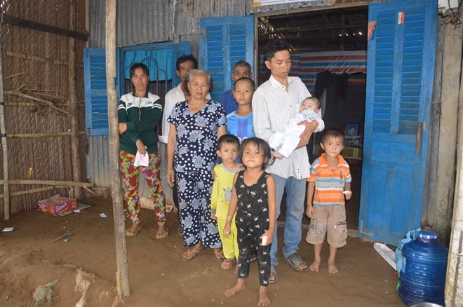 Gia đình anh Sơn Mêl bên căn nhà lá lụp sụp.