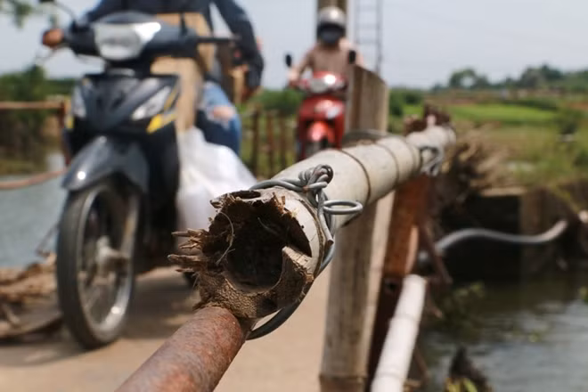 Để gia cố hai bên lan can cầu, người dân phải dùng những thanh tre buộc tạm để gia cố bảo đảm an toàn khi đi qua cầu.