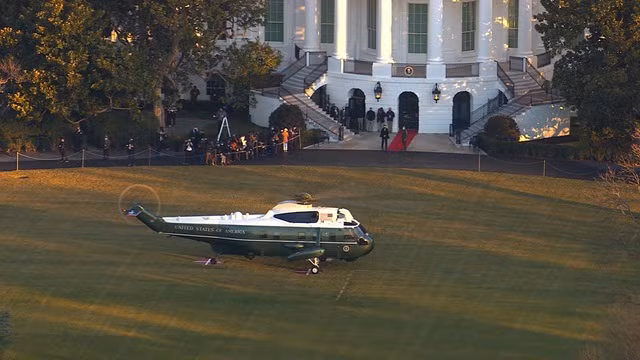 Trực thăng Marine One đậu ở bãi cỏ gần Nhà Trắng trước khi đưa gia đình ông Trump rời đi. Ảnh: Guardian Trực thăng Marine One đậu ở bãi cỏ gần Nhà Trắng trước khi đưa gia đình ông Trump rời đi. Ảnh: Guardian