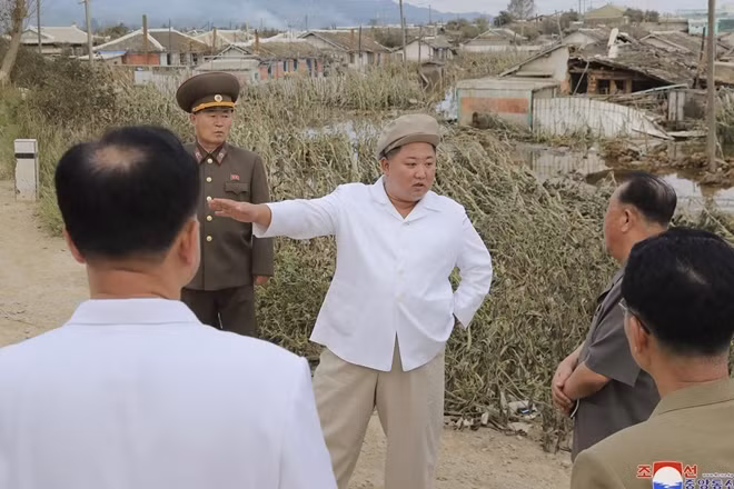 Ông Kim cùng quan chức trò chuyện cạnh các ngôi nhà bị hư hại do bão. Ảnh: KCNA