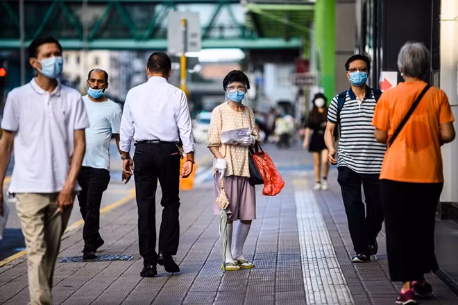 Người phụ nữ Hong Kong đeo khẩu trang và tấm chắn giọt bắn khi ra đường. Ảnh: NBCNews