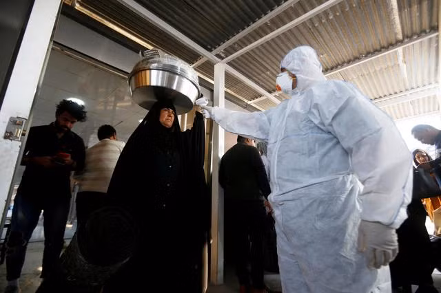 Nhân viên y tế kiểm tra thân nhiệt một phụ nữ tại một nhà thờ ở Iran. Ảnh: ITN
