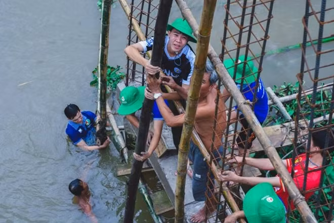 Ngâm mình trong nước, tham gia cùng với người dân sửa chữa, xây cầu nông thôn.