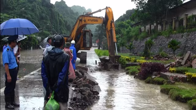 Máy xúc được huy động tạo đường thoát nước ngăn không cho dầu tràn vào nhà dân.