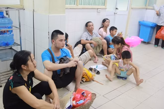 Người nhà bệnh nhi la liệt nằm, ngồi chờ đợi kết quả khám bệnh và làm thủ tục nhập viện. Ai cũng mệt mỏi vì nắng nóng.