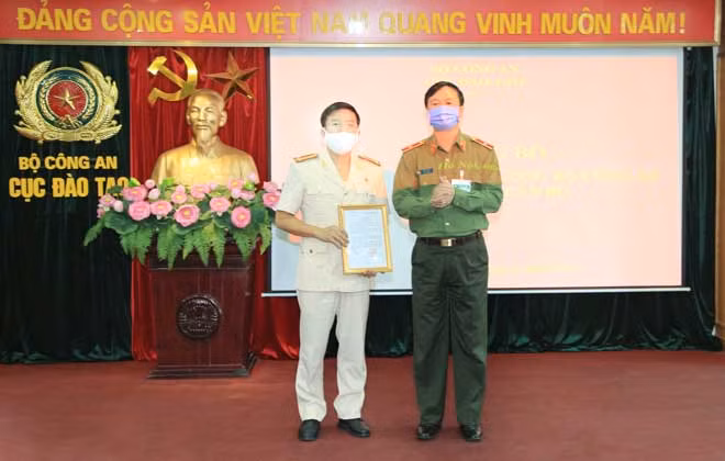 Thiếu tướng Bùi Minh Giám trao Quyết định cho Thượng tá Nguyễn Anh Tuấn, Phó Cục trưởng Cục Đào tạo.