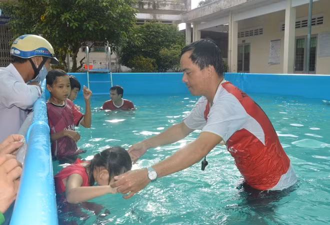 Thầy giáo Ngô Trọng Tính hướng dẫn, thị phạm cho các em học sinh tập bơi.