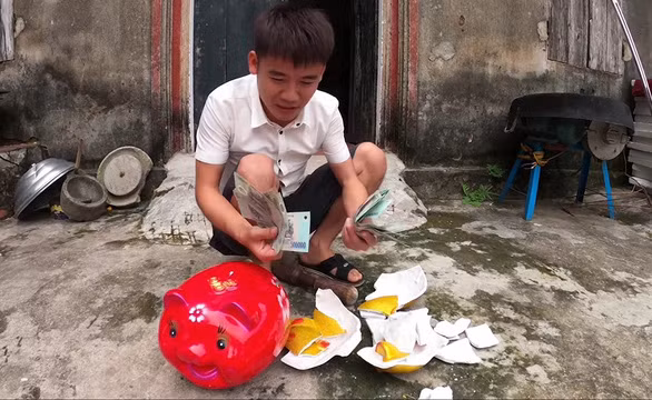Hưng Vlog đập heo đất để lấy tiền. (Nguồn ảnh báo Tuổi trẻ). Hưng Vlog đập heo đất để lấy tiền. (Nguồn ảnh báo Tuổi trẻ).
