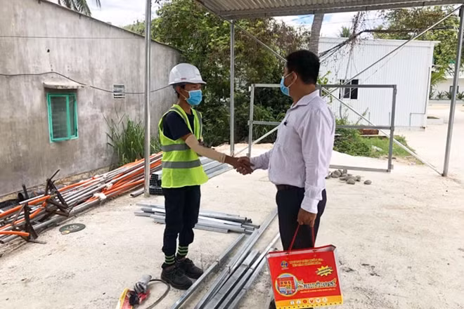 Ông Trần Lê Hữu Thọ (bên phải) xin lỗi và tặng quà cho anh Trần Văn Em.
