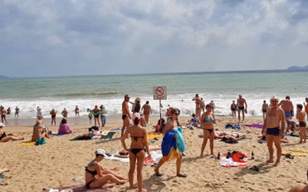 Du khách nước ngoài tắm nắng, đón gió trên bãi cát và tắm biển Nha Trang sáng 19/2.