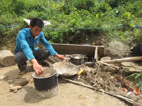 Anh Phàn Sài Mìn đang thu gom lại những vật dụng trong gia đình còn sót lại dưới đống đổ nát.