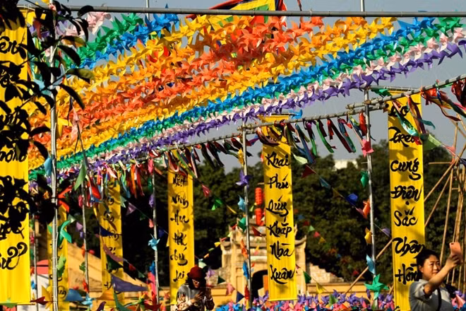 Những chiếc chong chóng đủ sắc màu được treo cao tạo thành một con đường đủ mọi màu sắc rực rỡ kết hợp với những lời chúc Tết 2 bên đường tạo lên không khí xuân ngập tràn .