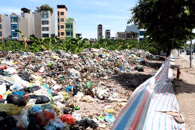 Thứ duy nhất ngăn cách giữa núi rác này và con đường tấp nập phương tiện bên ngoài chỉ là một lớp bạt...