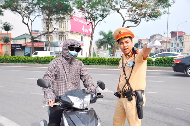 Một chiến sĩ CSGT tại nút lên cầu Chương Dương hướng dẫn người tham gia giao thông nhanh chóng về nhà trốn nắng nóng khắc nghiệt của mùa hè.