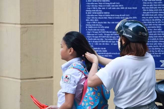 Một em gái được mẹ buộc tóc trước khi vào lễ khai giảng tại trường PTCS Xã Đàn.
